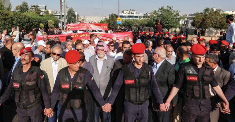 Jordanian security forces create a security perimeter around protesters participating in the "March of Anger" demonstration leading to the US embassy headquarters in the Jordanian capital Amman on June 21, 2019, against the US President Donald Trump's "Deal of the Century" and the US-led Middle East economic conference in Bahrain. (AFP)