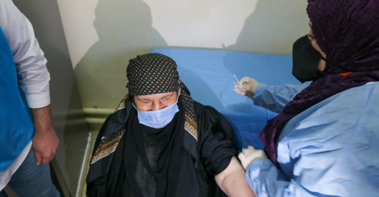 لاجئة سورية تتلقى لقاح كورونا في المركز الصحي بمدينة المفرق (المفوضية)