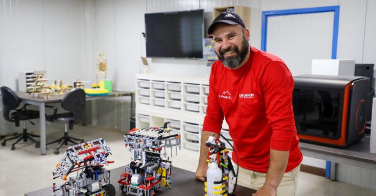 مدرب الروبوتكس في مخيم الزعتري مروان الزعبي وامامه على الطاولة الانسان الآلي لتعقيم اليدين (عمان نت)