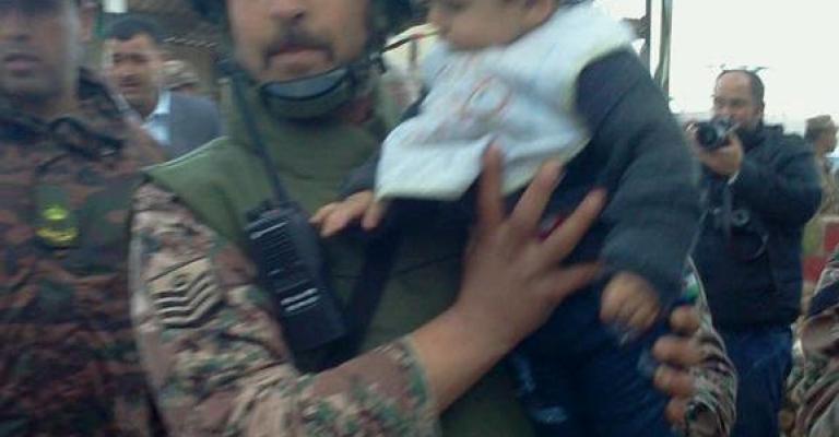 احد جنود حرس الحدود يحمل طفل سوري - عدسة محمد عرسان 