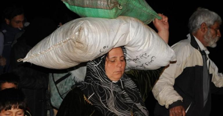 لاجئة تحمل بعض حاجياتها خلال النزوح للاردن