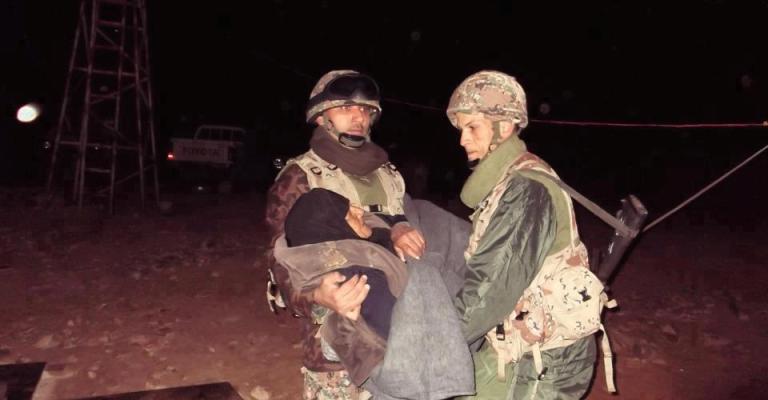 جنود أردنيين يحملون لاجئة مسنة