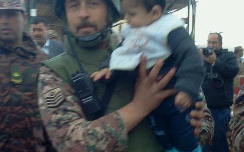احد جنود حرس الحدود يحمل طفل سوري - عدسة محمد عرسان  