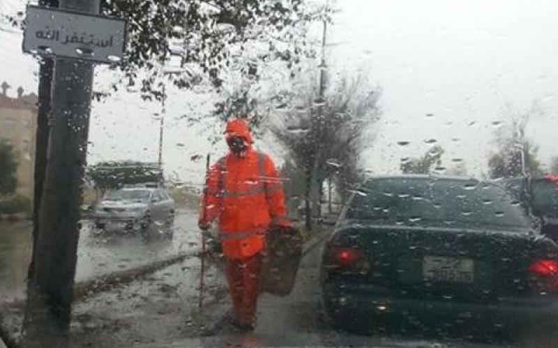 عامل وطن اثناء قيامه بعمله تحت المطر في العاصمة عمان.. تصوير الزميل داود كتاب