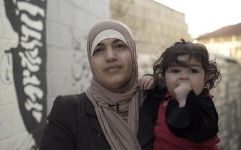 امرأة أردنية متزوجة من رجل أجنبي، تحمل طفلتها، وهي واحدة من أبنائها الأربعة غير الحاصلين على الجنسية الأردنية. الصورة © أماندا بايلي لـ هيومن رايتس ووتش